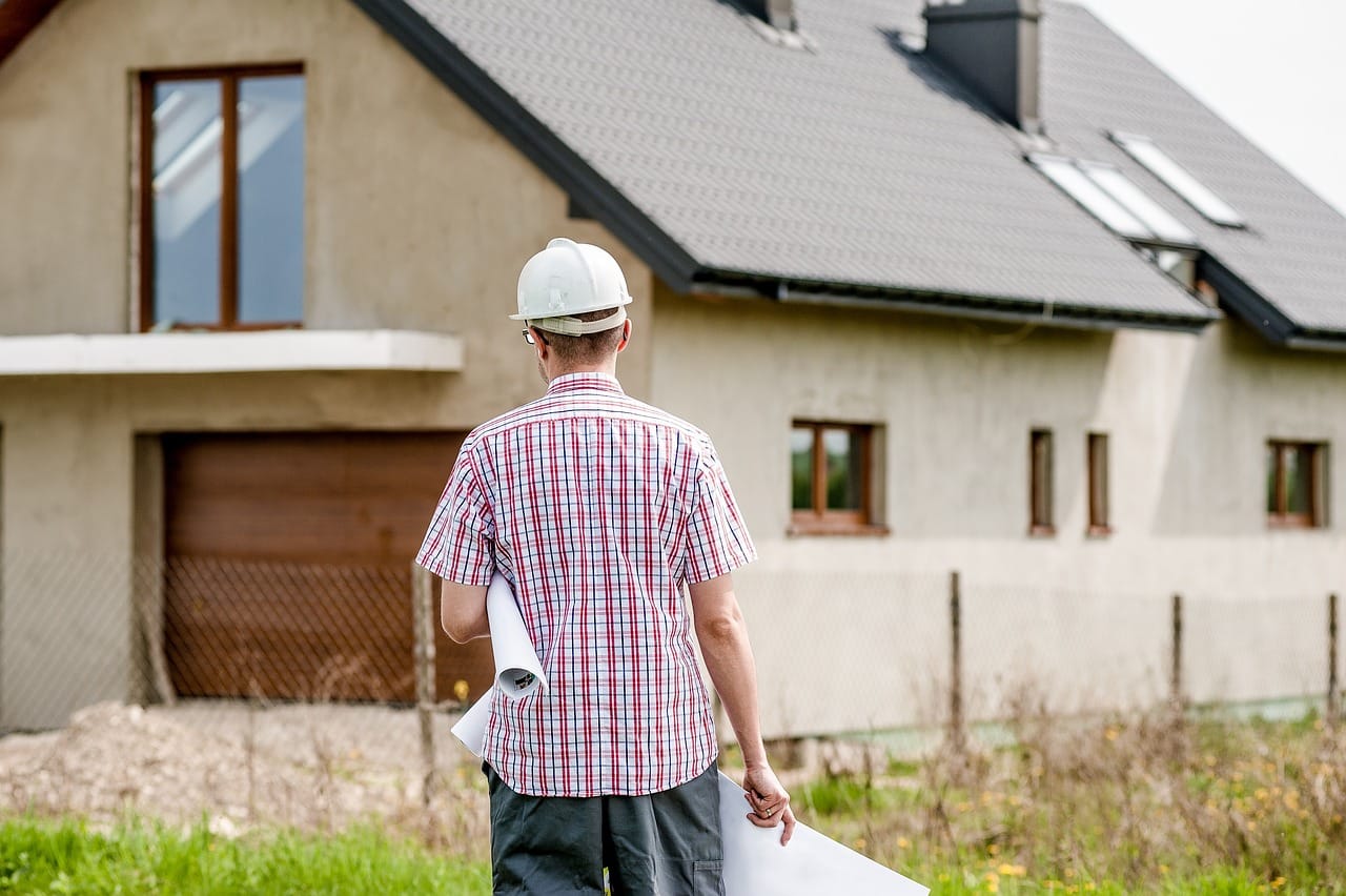 Sanierung finanzieren: Bauingenieur steht vor sanierungsbedürftiger Immobilie