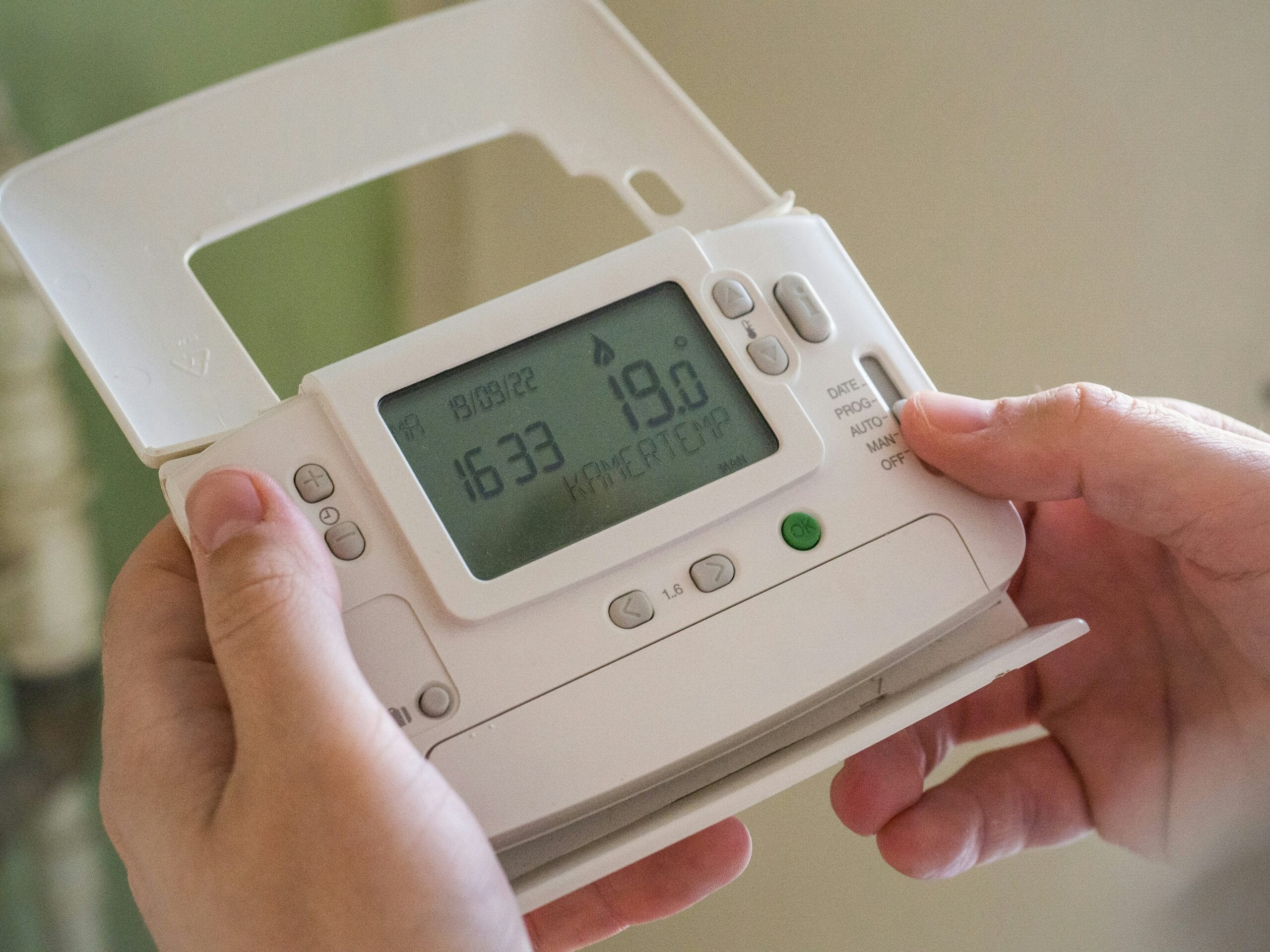 Person hält Thermostat in Händen